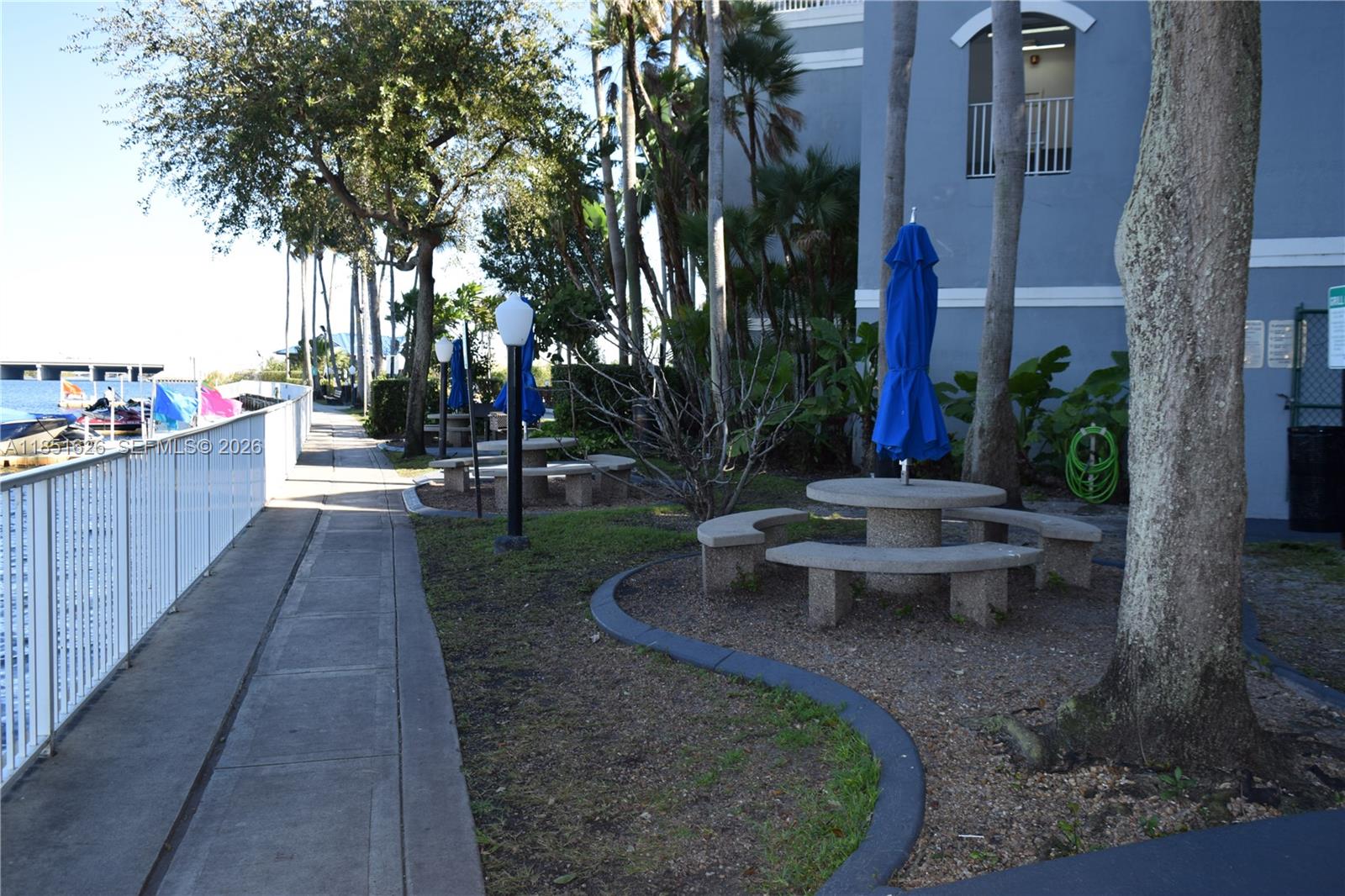 5091 Northwest 7th Street, Unit 711 Miami, FL 33126 - Photo 33 of 72 a view of a patio with table and chairs potted plants and large tree