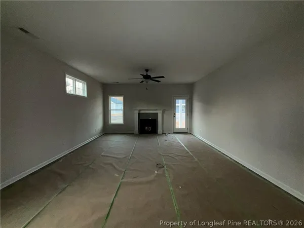 a view of an empty room with a fireplace and a window