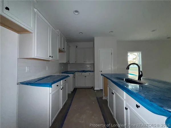 a kitchen with granite countertop white cabinets and sink
