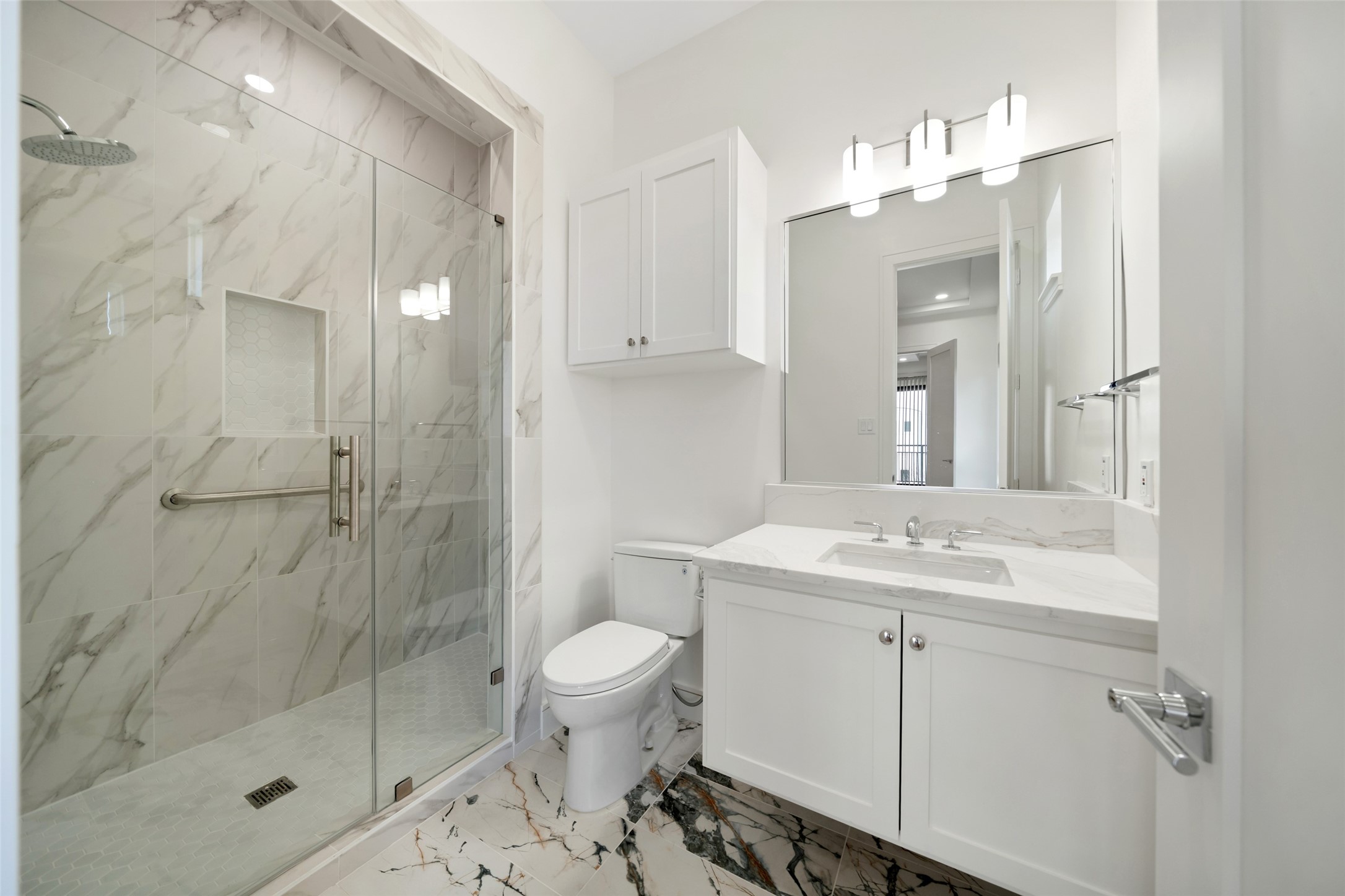 1839 Colquitt Street Houston, TX 77098 - Photo 11 of 19 En-suite modern bathroom #2 features a marble-tiled walk-in shower with a glass door, elegant vanity with a large mirror, and contemporary lighting. The design is clean and sophisticated, offering a luxurious feel.