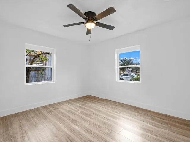 a view of an empty room with a window and a ceiling fan