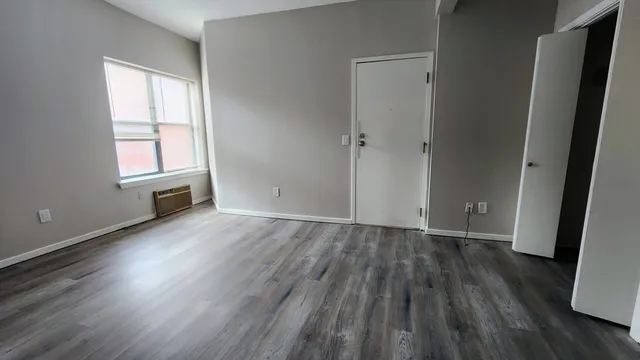 an empty room with wooden floor and window