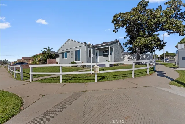 a view of a house with a small yard and a large tree
