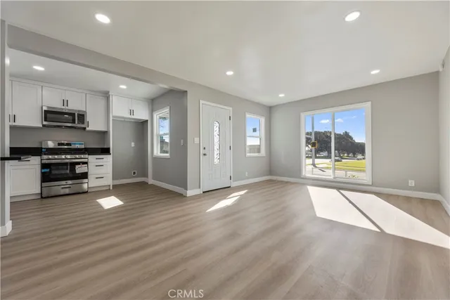 a view of an empty room with a window and wooden floor
