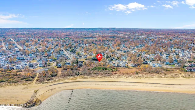 an aerial view of ocean and residential houses with outdoor space