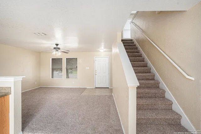 a view of an empty room with stairs and a window