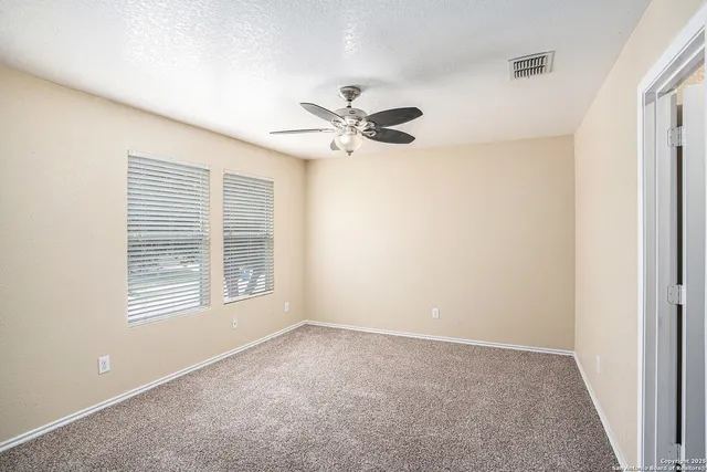 an empty room with windows and fan