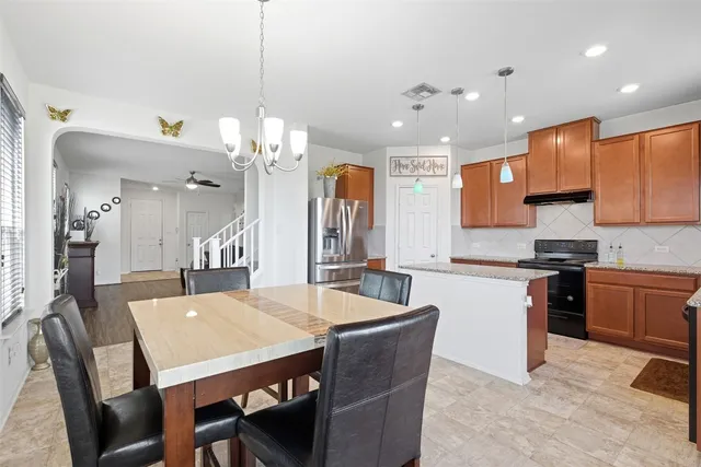 a kitchen with a dining table chairs stainless steel appliances and cabinets