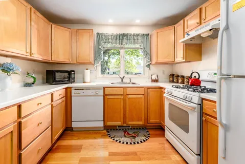 a kitchen with stainless steel appliances granite countertop a sink a stove cabinets and a window