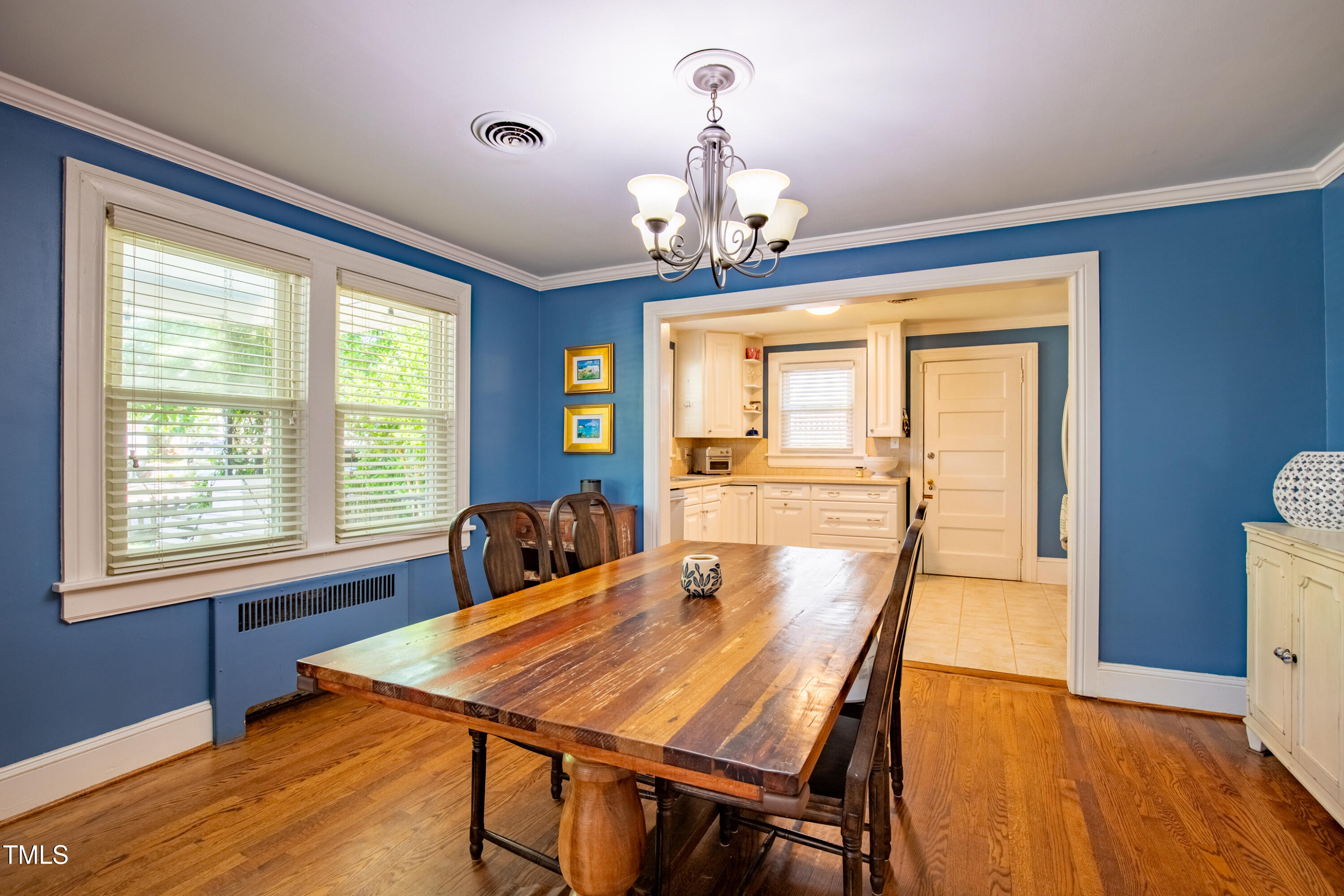 1714 Carson Street Raleigh, NC 27608 - Photo 14 of 38 a dining room with wooden floor a chandelier a wooden table and chairs