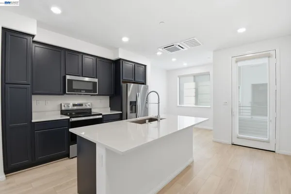 a kitchen with kitchen island a sink stainless steel appliances and cabinets