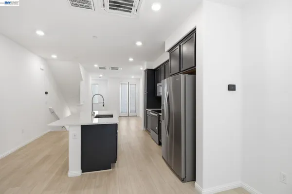a kitchen with stainless steel appliances kitchen island granite countertop a refrigerator and a sink