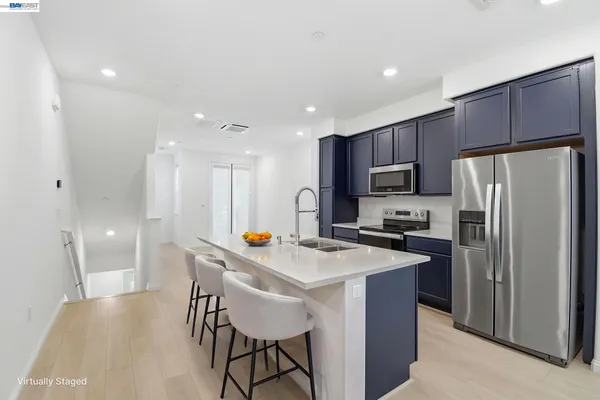 a kitchen with a refrigerator a stove a sink a dining table and chairs