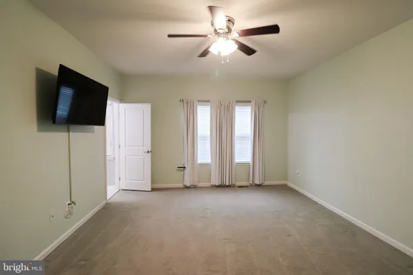 a view of an empty room with a ceiling fan and a window