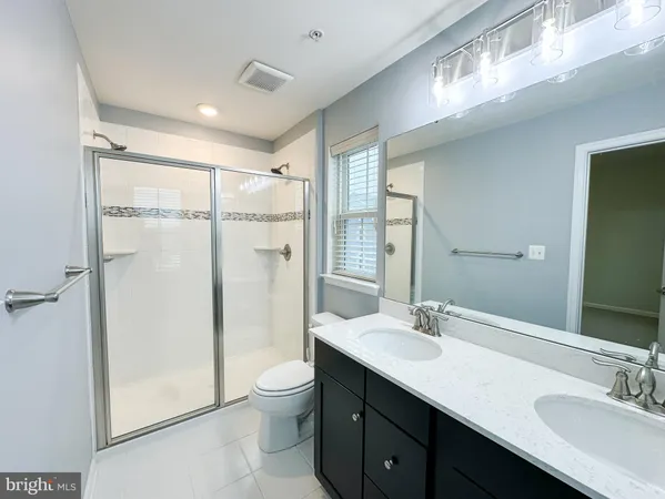 a bathroom with a double vanity sink toilet mirror and shower