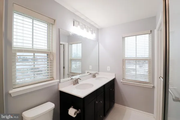 a bathroom with a sink toilet a mirror and next to a window