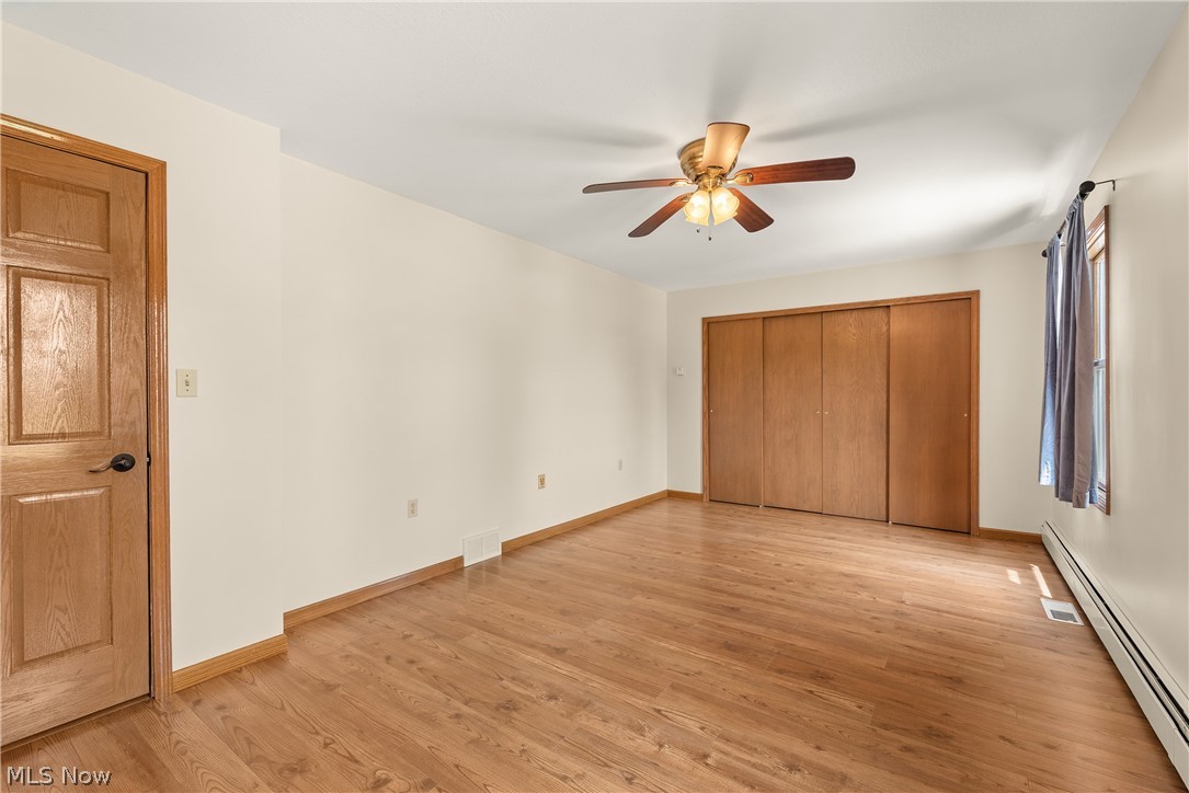 9990 Broadview Road Broadview Heights, OH 44147 - Photo 35 of 47 Unfurnished bedroom featuring a baseboard radiator, light wood-style flooring, a ceiling fan, and a closet