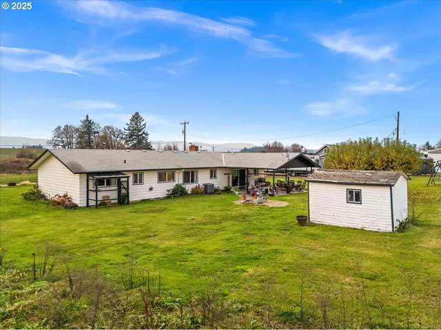 a view of a house with a big yard and large tree