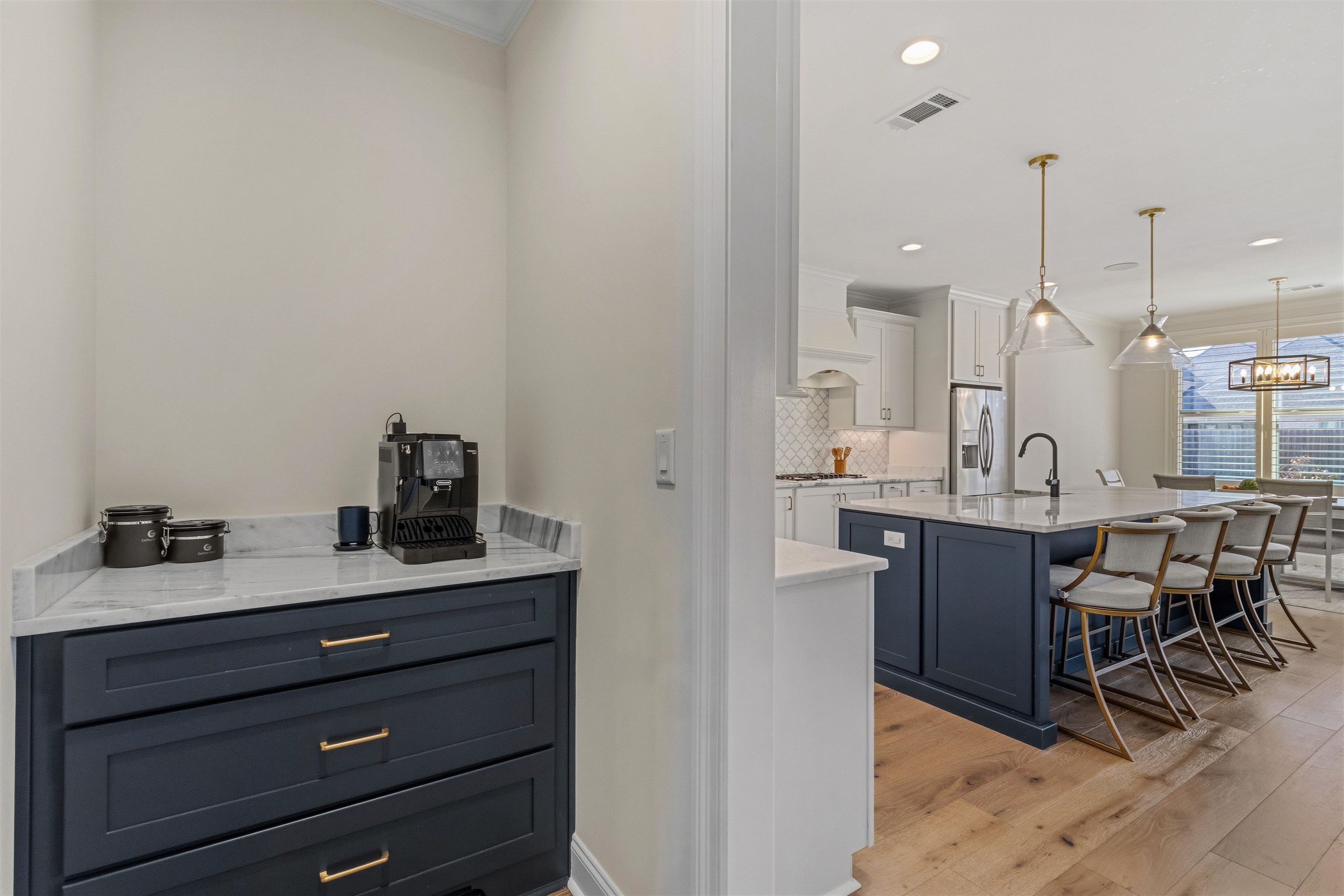 4757 Carousel Lane Collierville, TN 38017 - Photo 15 of 39 Bar area featuring light wood-type flooring, light stone counters, two tone cabinets, hanging light fixtures, and stainless steel fridge with ice dispenser