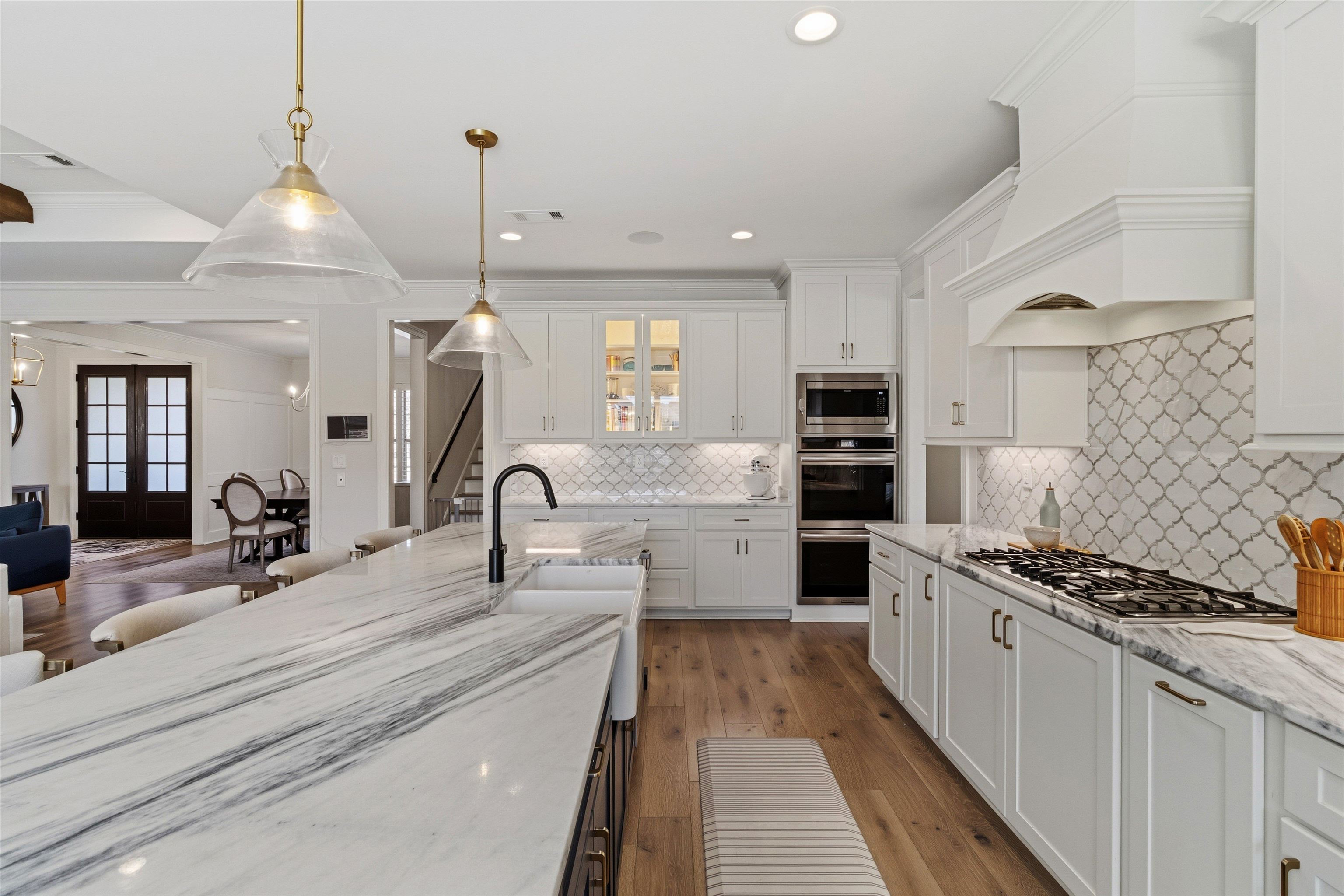 4757 Carousel Lane Collierville, TN 38017 - Photo 10 of 39 Kitchen featuring decorative light fixtures, white cabinets, light stone counters, dark wood-style flooring, and stainless steel appliances