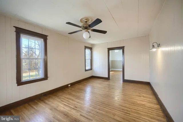 a view of an empty room with a window and wooden floor