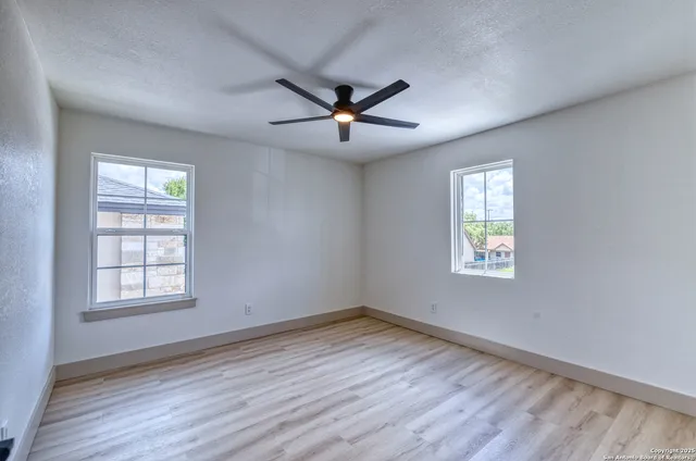 a view of empty room with wooden floor and fan