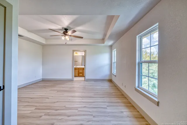 a view of an empty room with window and wooden floor