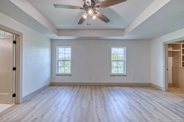 a view of an empty room with wooden floor and window