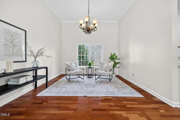 a dining room with wooden floor a chandelier a glass table and a window