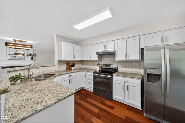 a kitchen with stainless steel appliances granite countertop a sink stove microwave and refrigerator