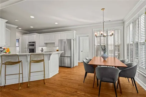 a kitchen with stainless steel appliances kitchen island granite countertop a table chairs and a refrigerator