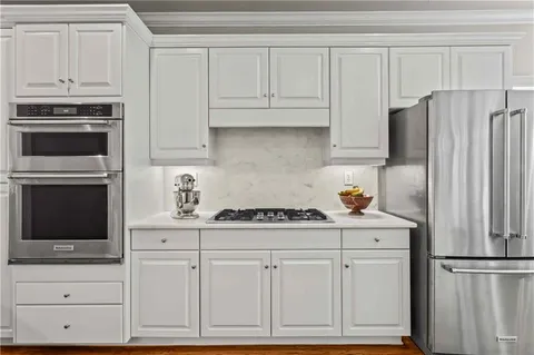 a kitchen with granite countertop white cabinets and stainless steel appliances