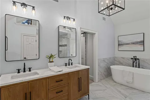 a bathroom with double vanity sinks a mirror and a bathtub