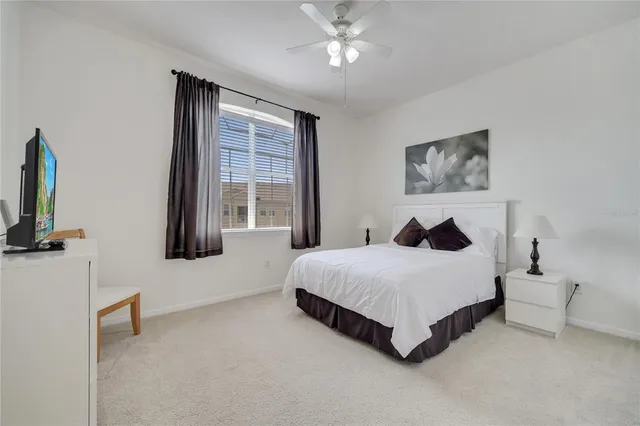 a spacious bedroom with a bed a couch and a flat tv screen on dresser