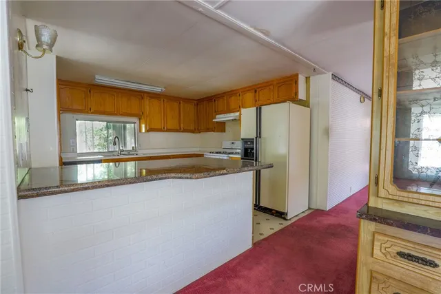 a kitchen with granite countertop a sink cabinets stainless steel appliances and a window