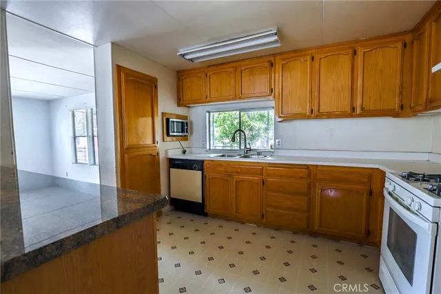a kitchen with stainless steel appliances a stove a sink a refrigerator white cabinets and wooden floor