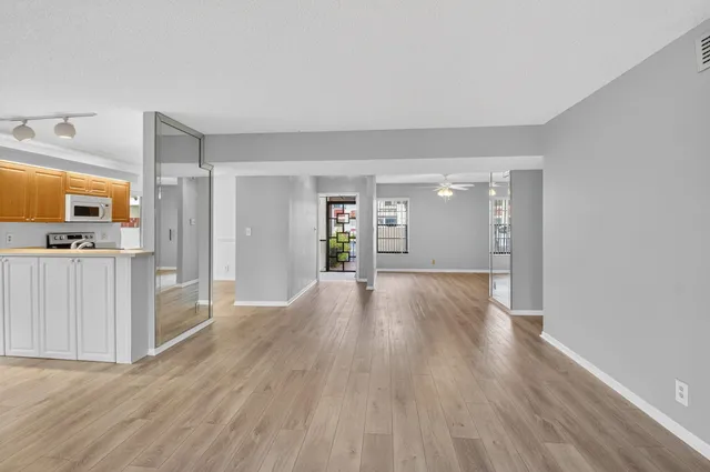 a view of a big room with wooden floor and a kitchen