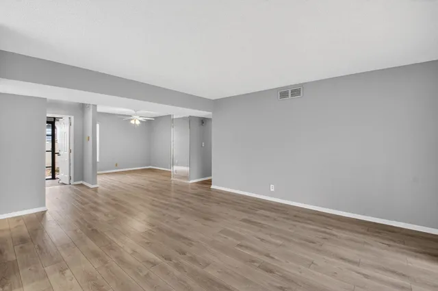a view of an empty room with wooden floor and closet