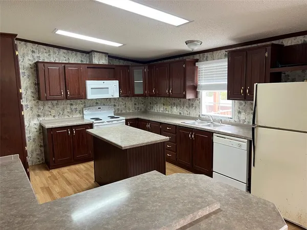 a kitchen with a sink a stove a refrigerator a center island and a window