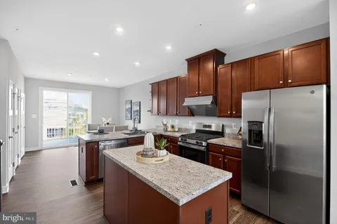 a kitchen with kitchen island granite countertop wooden cabinets a refrigerator and a stove