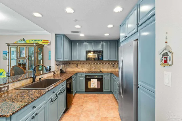 a kitchen with granite countertop kitchen island stainless steel appliances a sink stove and refrigerator