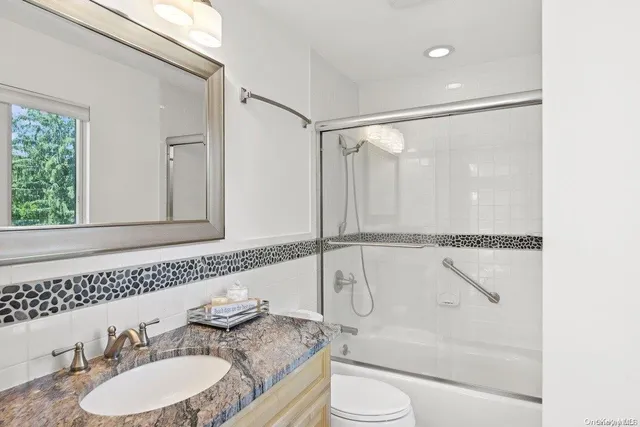 a bathroom with a granite countertop sink mirror vanity and toilet