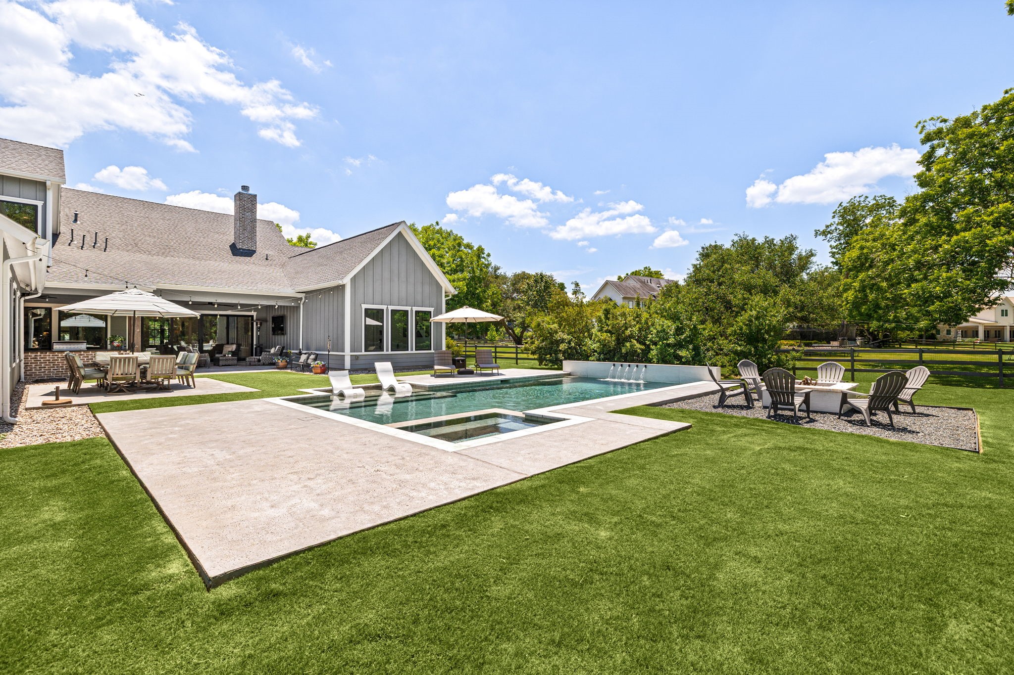 4311 Upper Oxbow Trace Fulshear, TX 77441 - Photo 42 of 49 Resort-style backyard featuring a sleek modern pool, tanning ledge, spa, fire pit area, and expansive outdoor entertaining spaces.