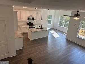 an open kitchen with white cabinets and wooden floor
