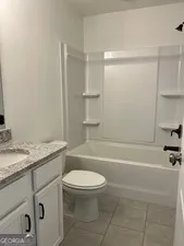 a bathroom with a granite countertop toilet a sink and a bathtub