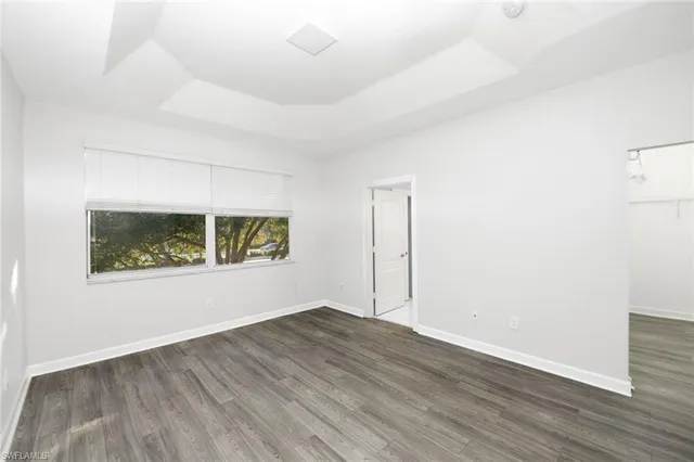 a view of an empty room with wooden floor and window
