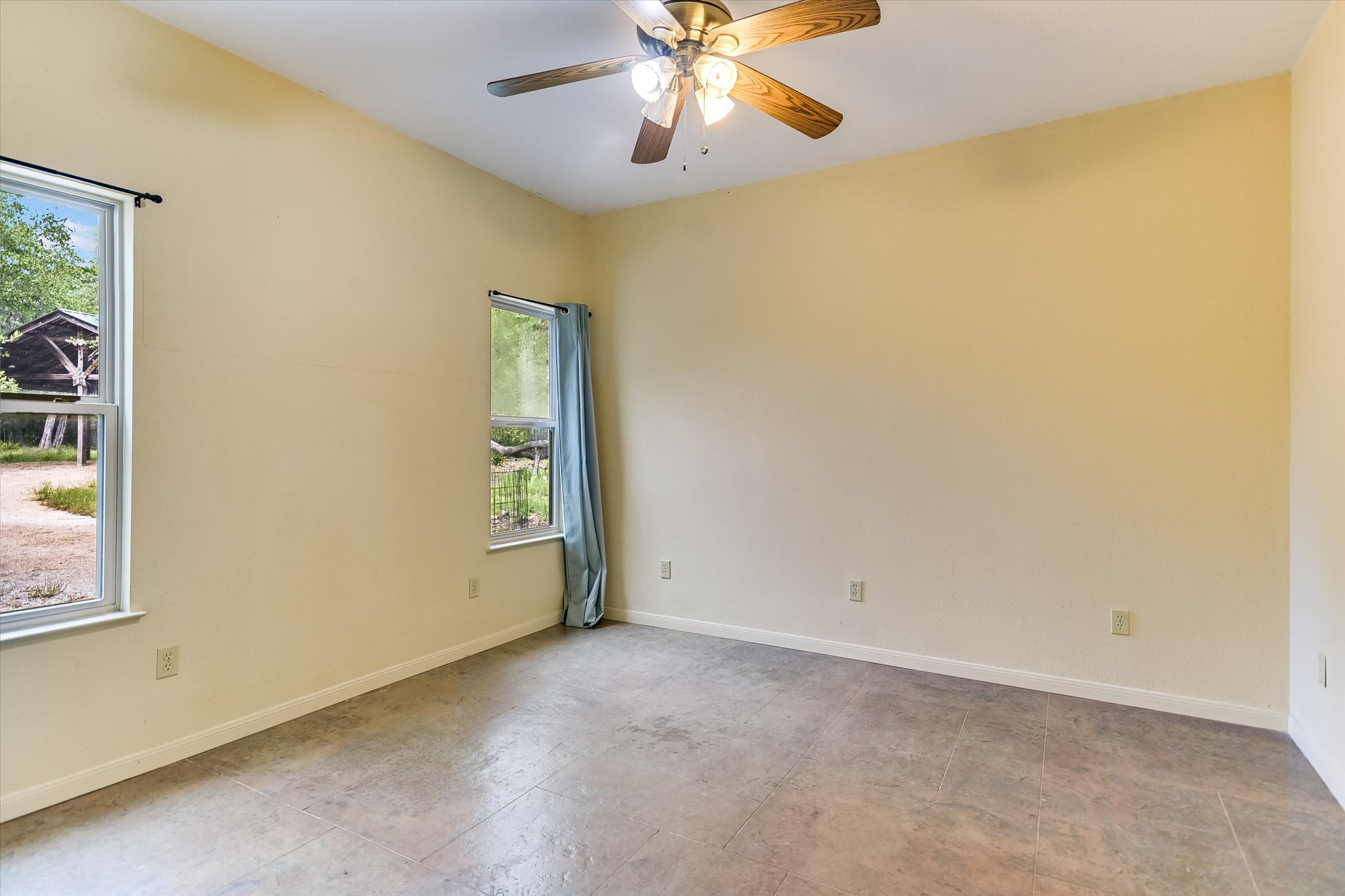 700 Cliffside Road Wimberley, TX 78676 - Photo 9 of 22 Room featuring sloped ceilings, two windows with white frames, and a ceiling fan with light fixture