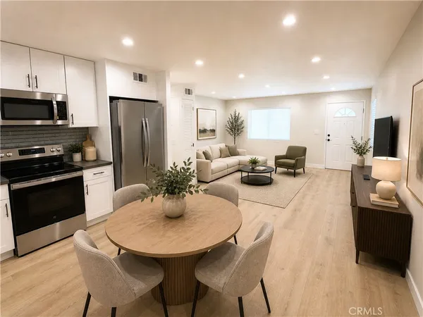 a kitchen with stainless steel appliances a dining table chairs a refrigerator and microwave
