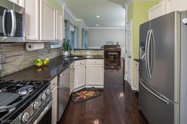 a kitchen with stainless steel appliances granite countertop a refrigerator a stove and a sink