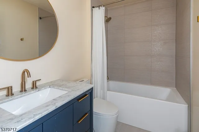 a bathroom with a granite countertop sink a toilet and bathtub
